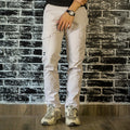 Person wearing a black t-shirt, white pants, and gray sneakers against a brick wall.